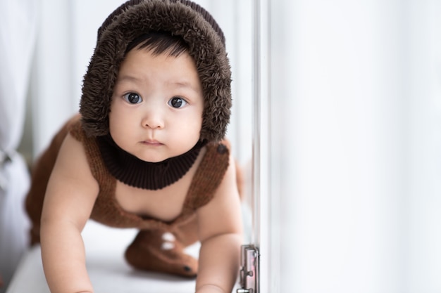 Un bébé cherche curieusement quelque chose à côté d'une fenêtre blanche