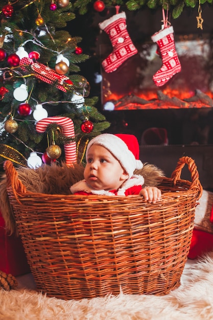 Bébé en costume de Père Noël joue aux décorations de Noël