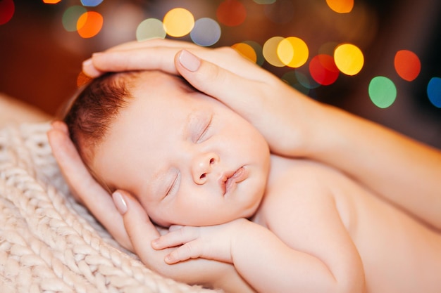 Bébé sur couverture dans les mains de la mère bokeh coloré sur fond