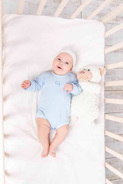 Bébé dans un berceau avec ours en peluche se couche ou se réveille le matin concept de famille et de naissance