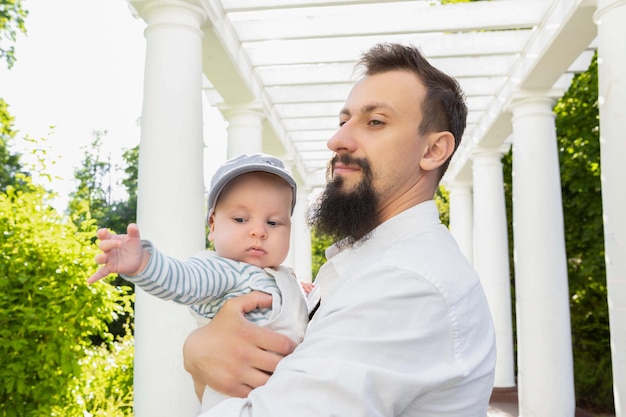 Bébé dans les bras de papa par une journée ensoleillée sur fond clair