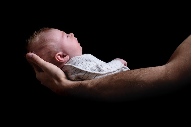 Bébé dans les bras de son père. Notion de naissance. Vue latérale noire. Isolé.