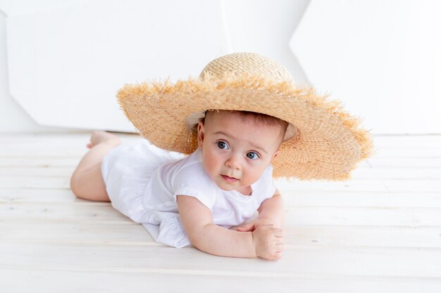 Photo un bébé dans un chapeau de paille est couché dans une pièce lumineuse