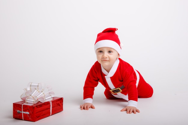 Un bébé dans un costume de père Noël sur fond blanc
