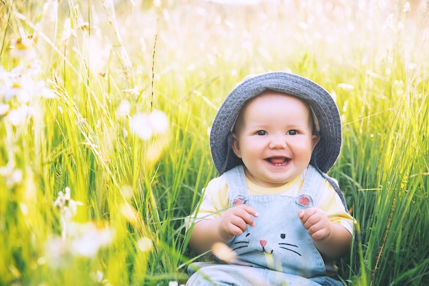 Bébé dans la nature La plus mignonne petite fille souriante dans l'herbe verte avec des fleurs en été