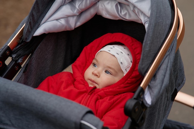 Bébé dans une poussette avec une capuche rouge