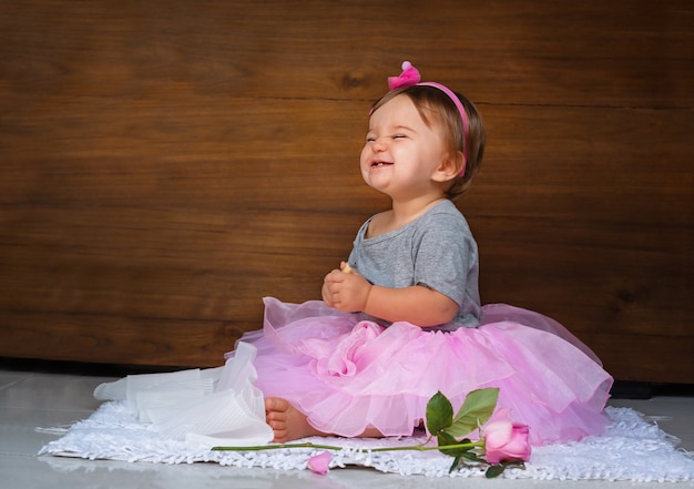 Bébé dans la robe rose. Enfant avec une rose et un cookie