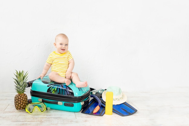 Bébé dans une valise avec des choses d'été pour les vacances, les voyages et le concept d'été, espace de copie