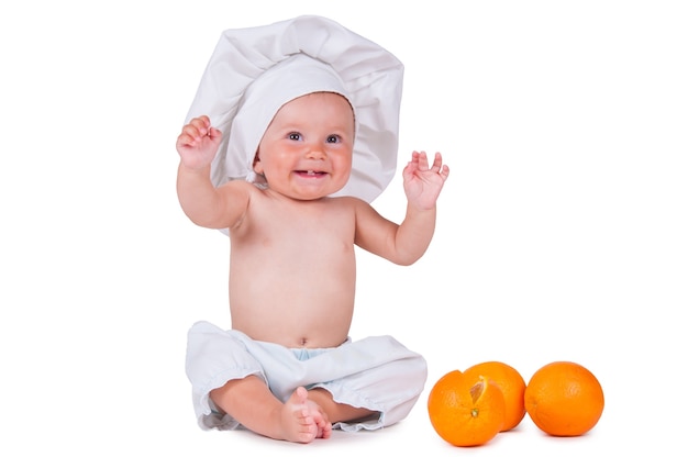 bébé dans un vêtement de chef mange orange