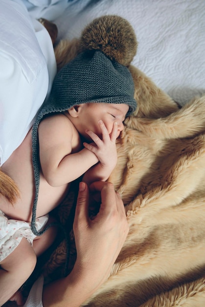 Bébé dort sur une couverture avec la main de sa mère