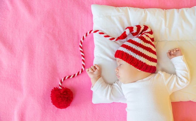 Bébé dort dans un bonnet de Noel, concept de Noël