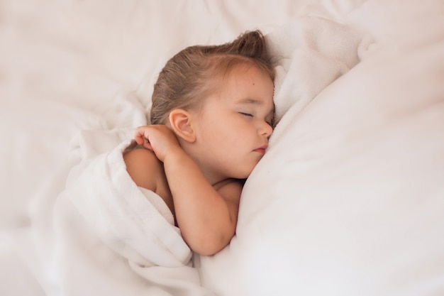 Bébé dort sur des draps blancs