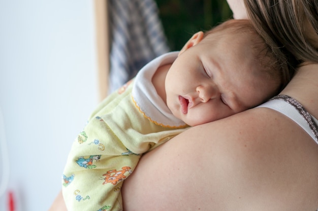 Le bébé dort sur l'épaule de la mère femme