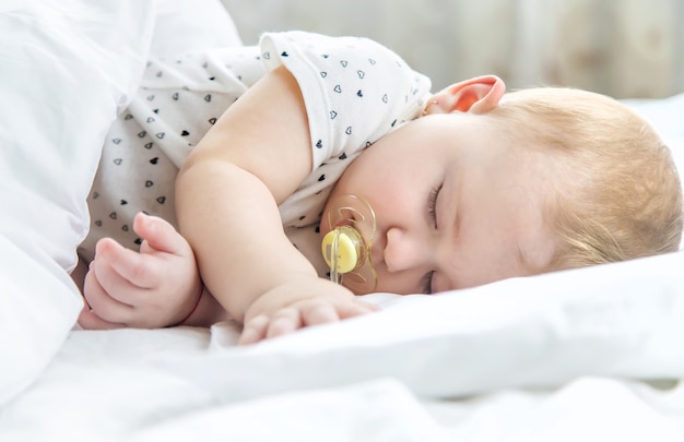 Bébé dort sur un lit blanc