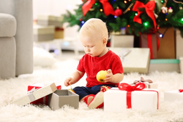 Bébé drôle avec des coffrets cadeaux et un arbre de Noël