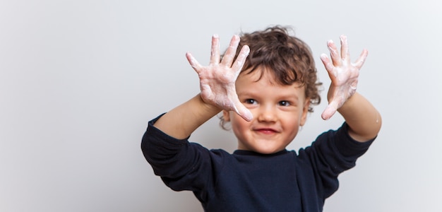 bébé drôle et joyeux montre ses paumes savonneuses