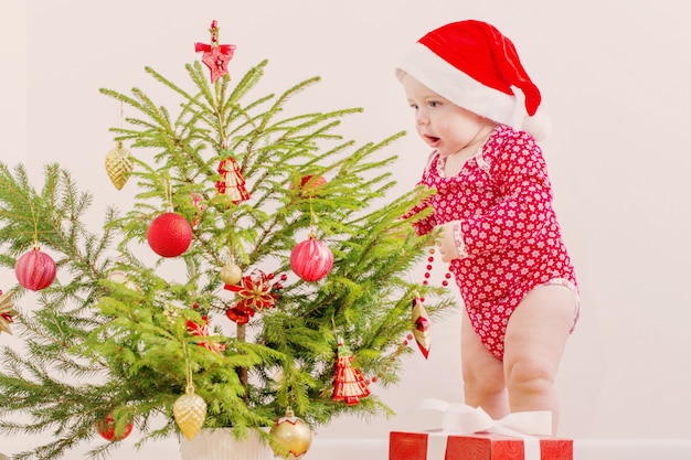 Bébé drôle avec petit sapin de Noël à la maison