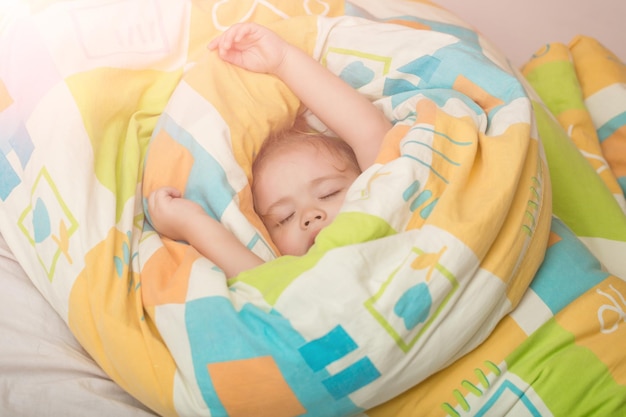 Bébé endormi dans une couverture colorée.