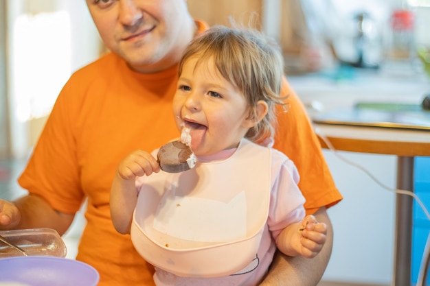 bébé essaie la crème glacée pour la première fois. tout-petit lécher la crème glacée avec une émotion heureuse. nourriture sucrée savoureuse