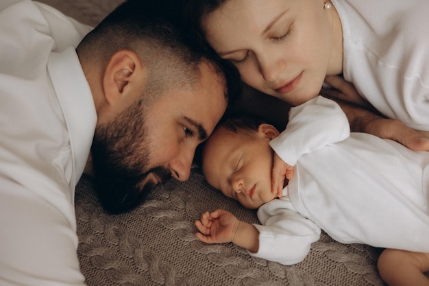 un bébé est allongé à côté d'un bébé et l'homme regarde la caméra