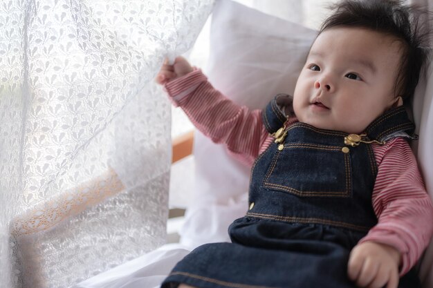 Un bébé est allongé sur un lit et regarde la caméra.