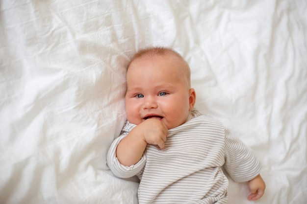 Le bébé est allongé à la maison sur le lit en souriant