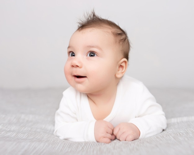 Le bébé est allongé sur le ventre sur le lit Un beau bébé sourit Maquette pour les cartes postales de célébration du design publicitaire