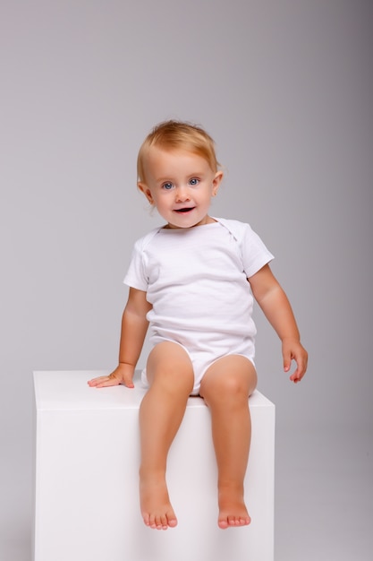 bébé est assis sur un cube en studio blanc,