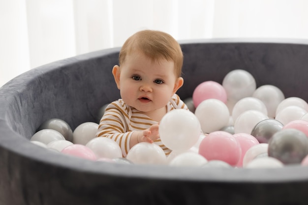 Photo un bébé est assis dans une fosse de balle tenant une balle