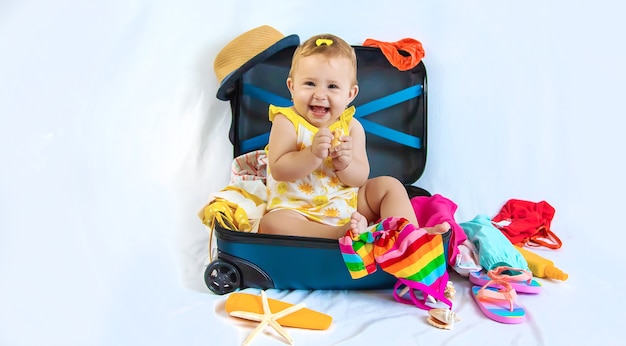 Bébé est assis dans une valise, se prépare pour un voyage