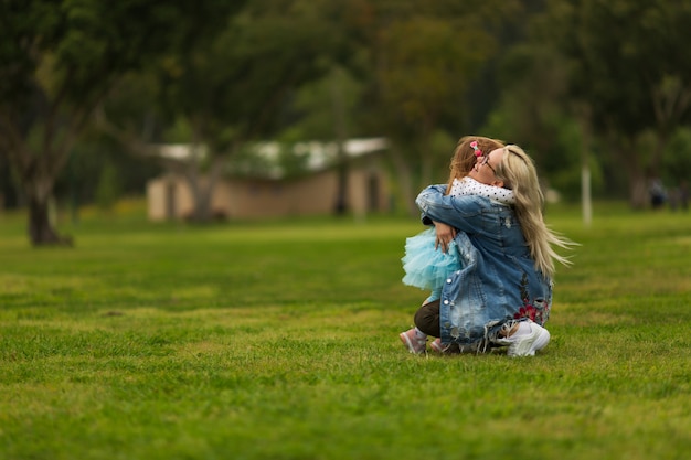 Bébé étreignant avec maman dans le parc sur l'herbe verte