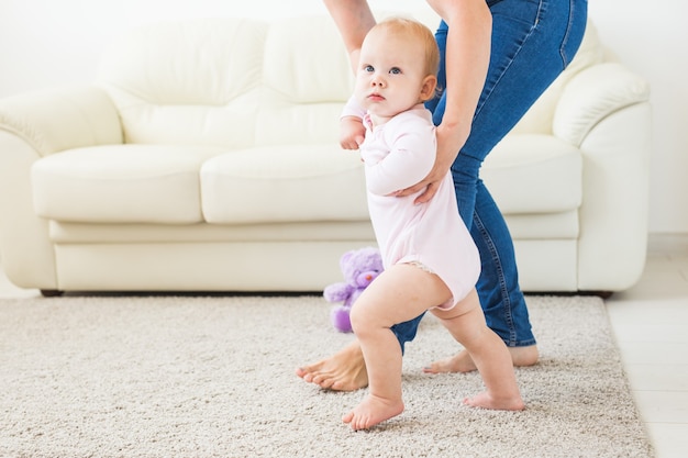 Bébé fait ses premiers pas avec l'aide de sa mère à la maison