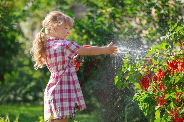 un bébé fille blonde marche par une journée ensoleillée prend soin du jardin