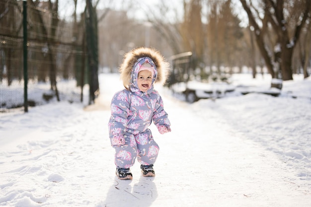 Bébé fille montrer la langue de l'enfant porter un habit de neige sur une journée d'hiver glaciale ensoleillée