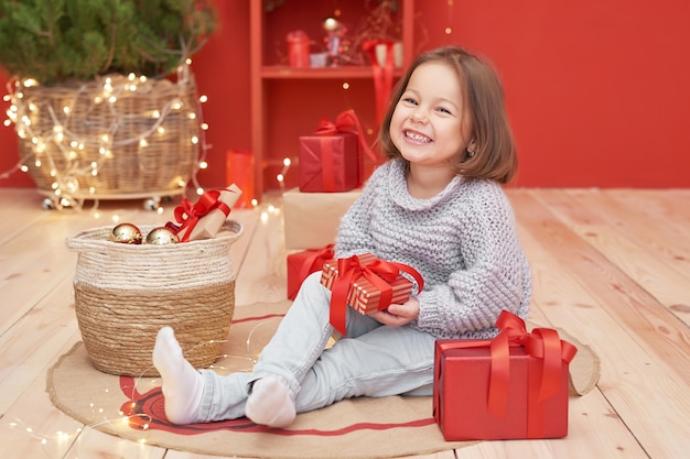 Bébé fille de Noël avec des cadeaux près de l'arbre de Noël