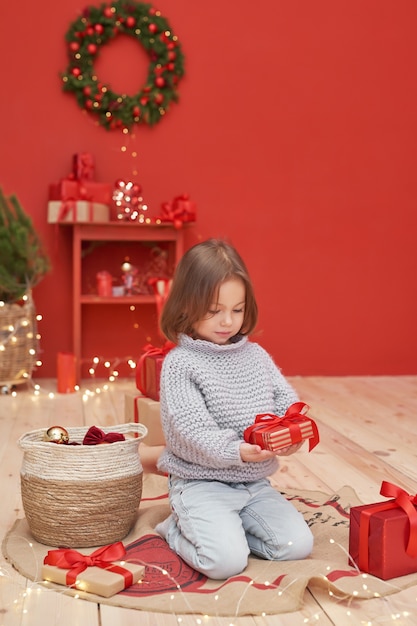 Bébé fille de Noël avec des cadeaux près de l'arbre de Noël