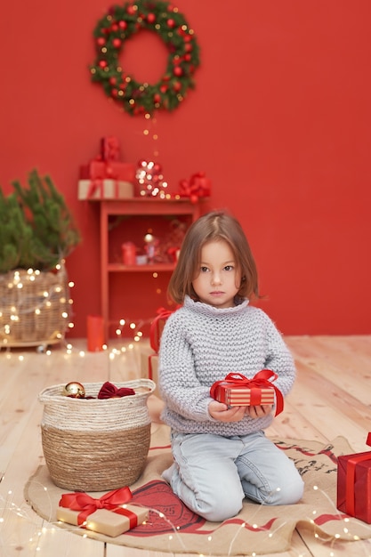 Bébé fille de Noël avec des cadeaux près de l'arbre de Noël