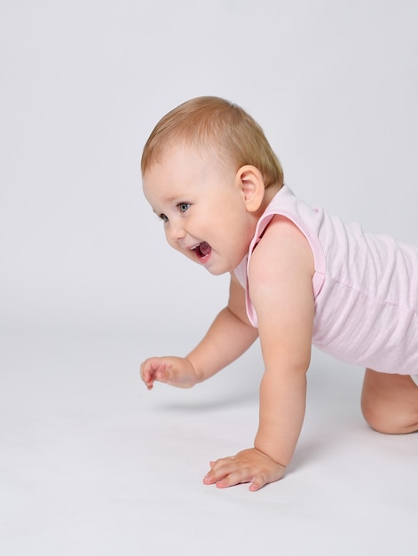 Un bébé sur fond blanc apprend à ramper les premiers pas de bébé