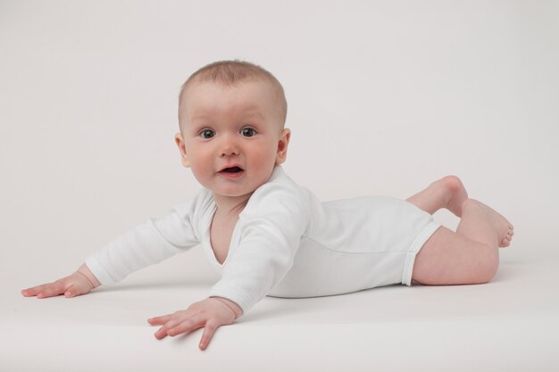 Bébé sur fond blanc dans un pyjama blanc