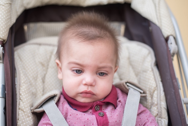 Bébé garçon aux yeux bleus dans la poussette de bébé