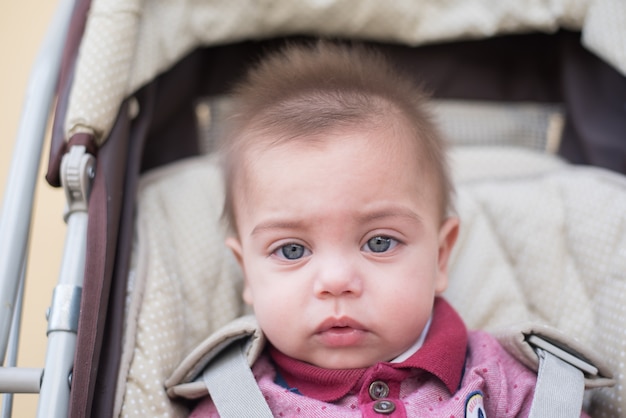 Bébé garçon aux yeux bleus dans la poussette de bébé