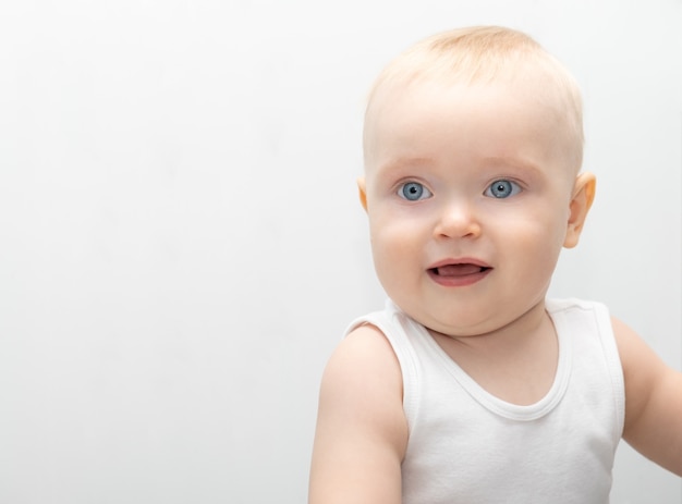 Bébé garçon blond avec de grands yeux bleus dans des vêtements de matériaux écologiques à la maison.