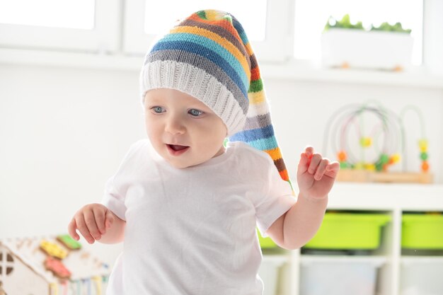 Bébé garçon en chapeau drôle apprend à marcher à la maison.