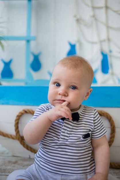 Photo bébé garçon dans une combinaison rayée tient un doigt dans sa bouche