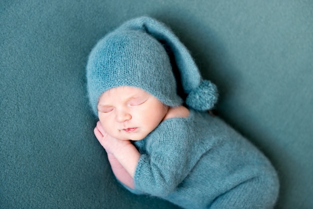 Bébé garçon dormant en costume de laine avec les pieds nus