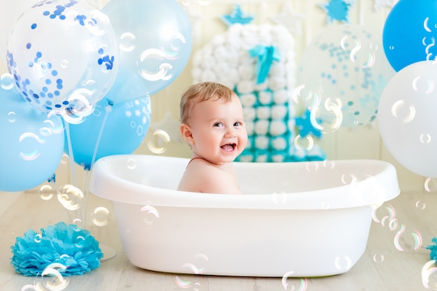 Bébé garçon fête son anniversaire dans un bain avec des ballons