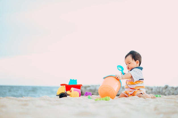 Bébé garçon jouant avec des jouets de plage avec sa mère sur la plage tropicale.