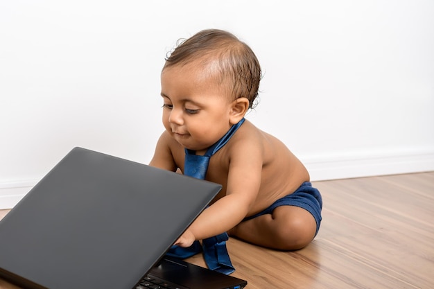 Bébé Garçon Jouant Avec Un Ordinateur Portable, Il Regarde La Caméra Porte  Une Cravate Est Torse Nu Assis Sur Un Plancher En Bois