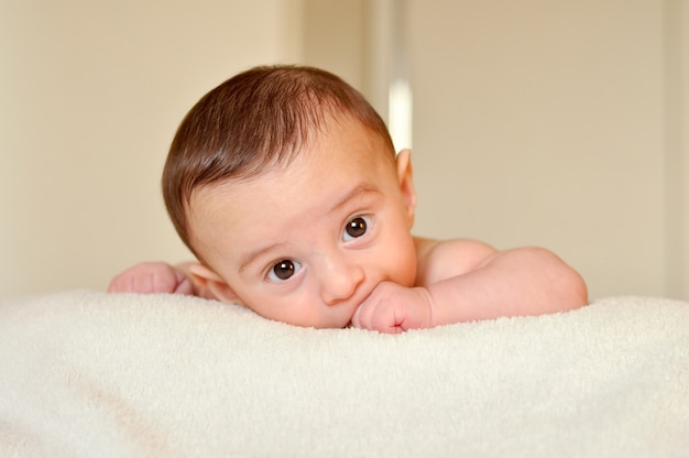 Bébé garçon main mordante et regarder la caméra