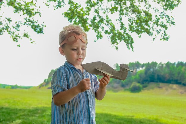 Un bébé garçon par l'avion joue sur la nature dans le parc. Garçon en vacances pilote.